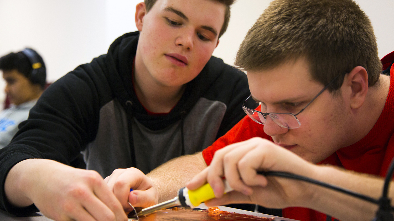 两个催化剂项目的学生在焊接电路。