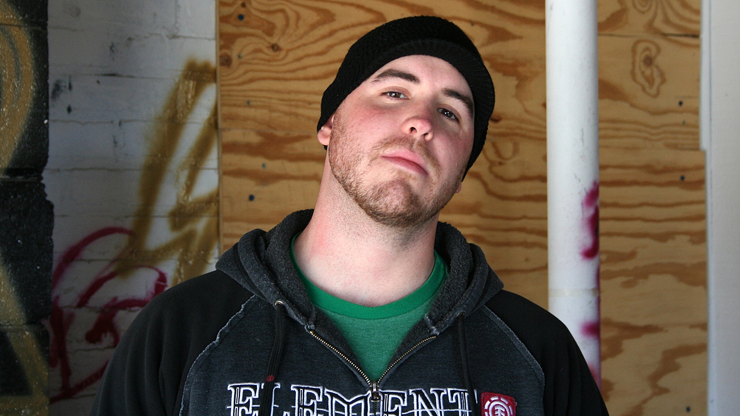 Josh Eure inside an abandoned building with graffiti in the background.