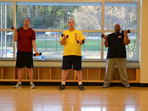 Three men lifting hand weights.