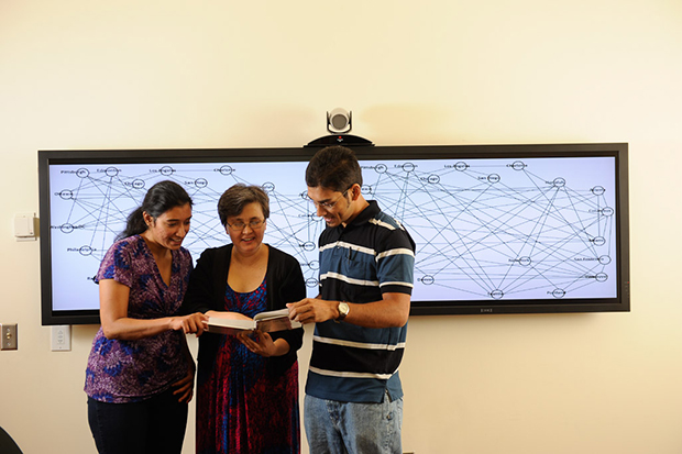 计算机科学博士。学生Kanchana Padmanabahn，Nagiza Samatova教授和博士。学生Arpan Chakraborty（左右）阅读他们共同编辑的数据挖掘教科书。