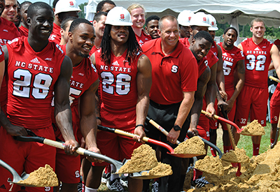 足球运动员帮助主教练戴夫·杜伦(中锋)破土动工。