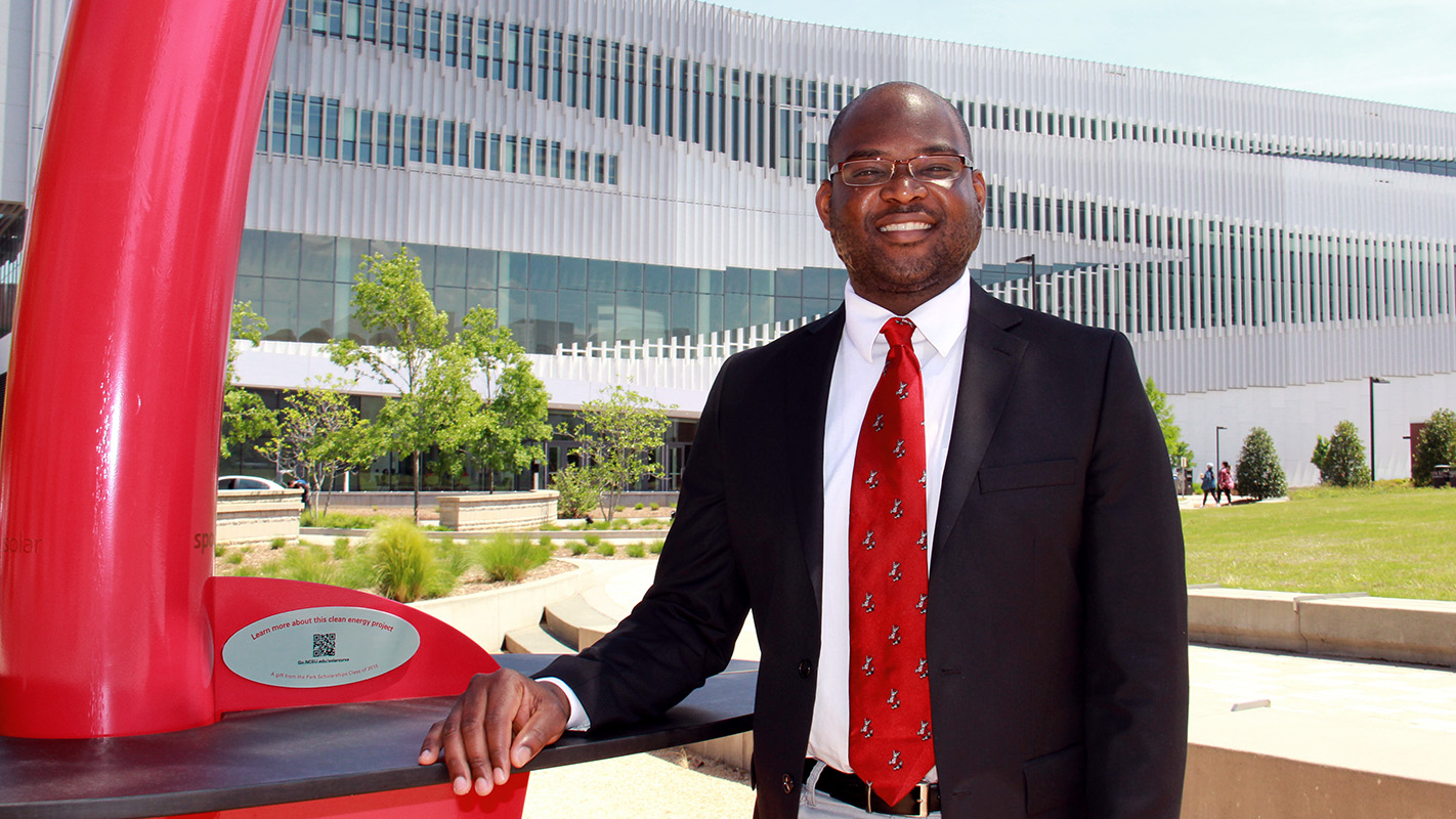 Keon Pettiway是修辞学、沟通学和数字媒体博士，他站在北卡罗来纳州亨特图书馆前的太阳能雕塑旁。