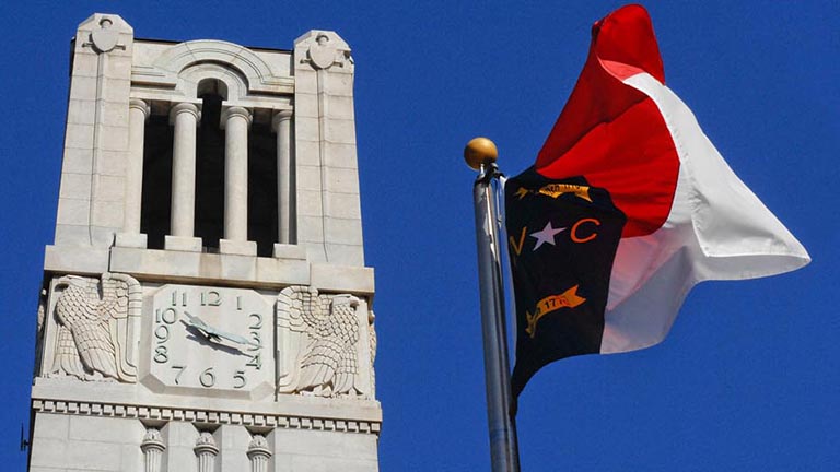 The NC State Memorial Bell Tower and the North Carolina state flag.