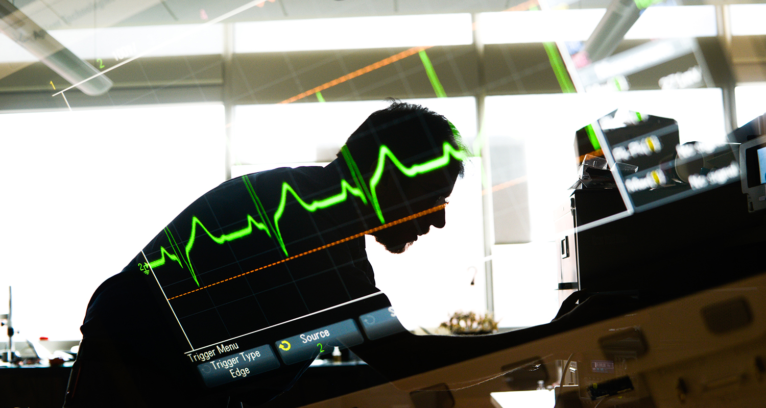 研究人员俯下身来，在实验桌上叠加了心脏监视器的图像。