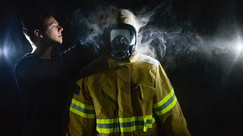 一名研究人员在烟雾缭绕的情况下测试了一套消防帽。