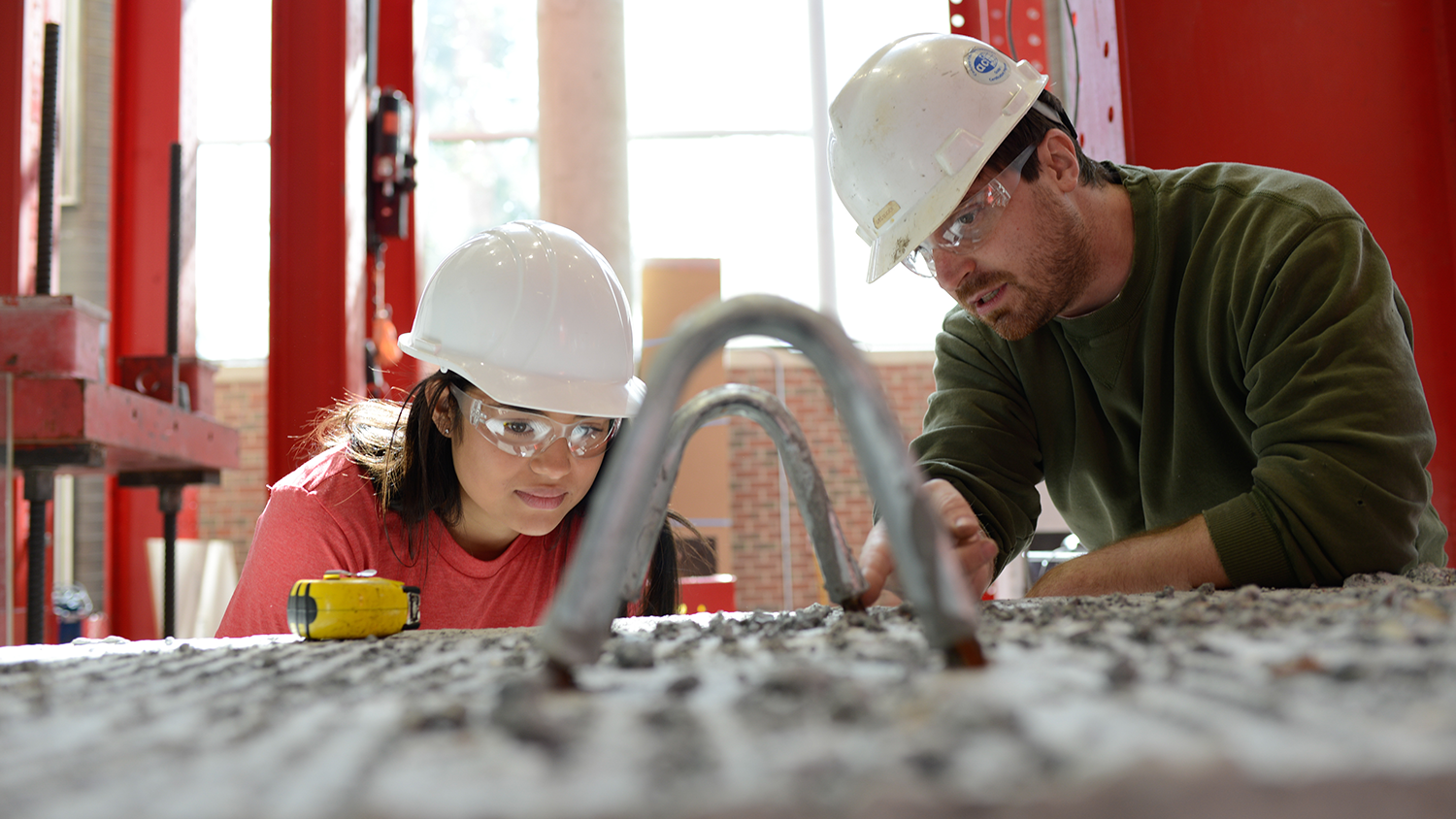 一名学生在NC州的建造设施实验室中戴着安全帽。