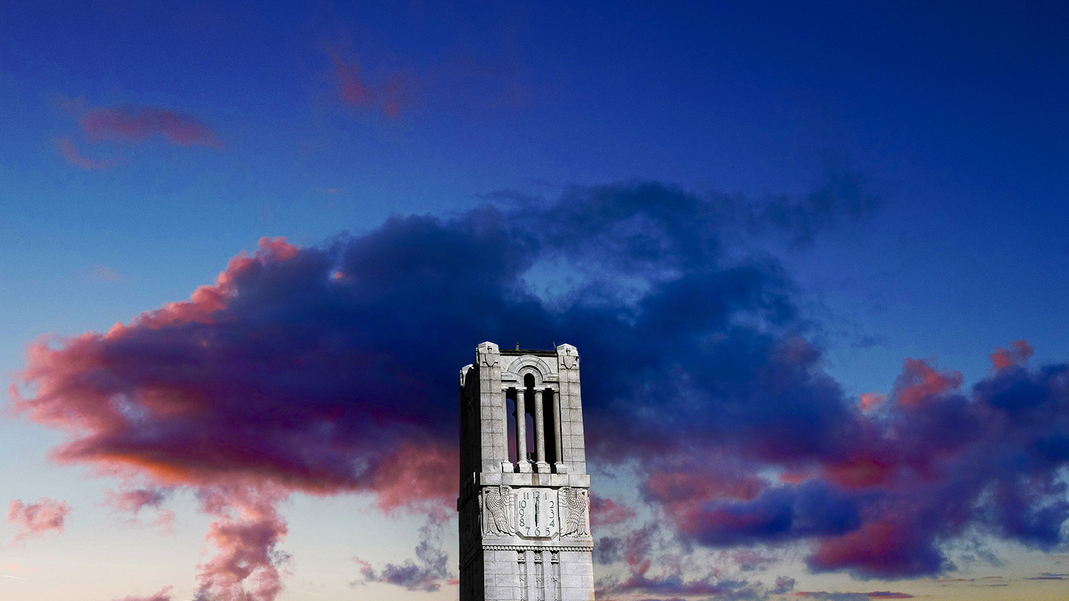 反对五颜六色的云彩的Belltower在日落。