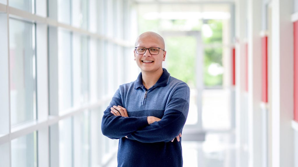 北卡罗来纳州立大学的学生Nikhil Milind站在窗户旁边