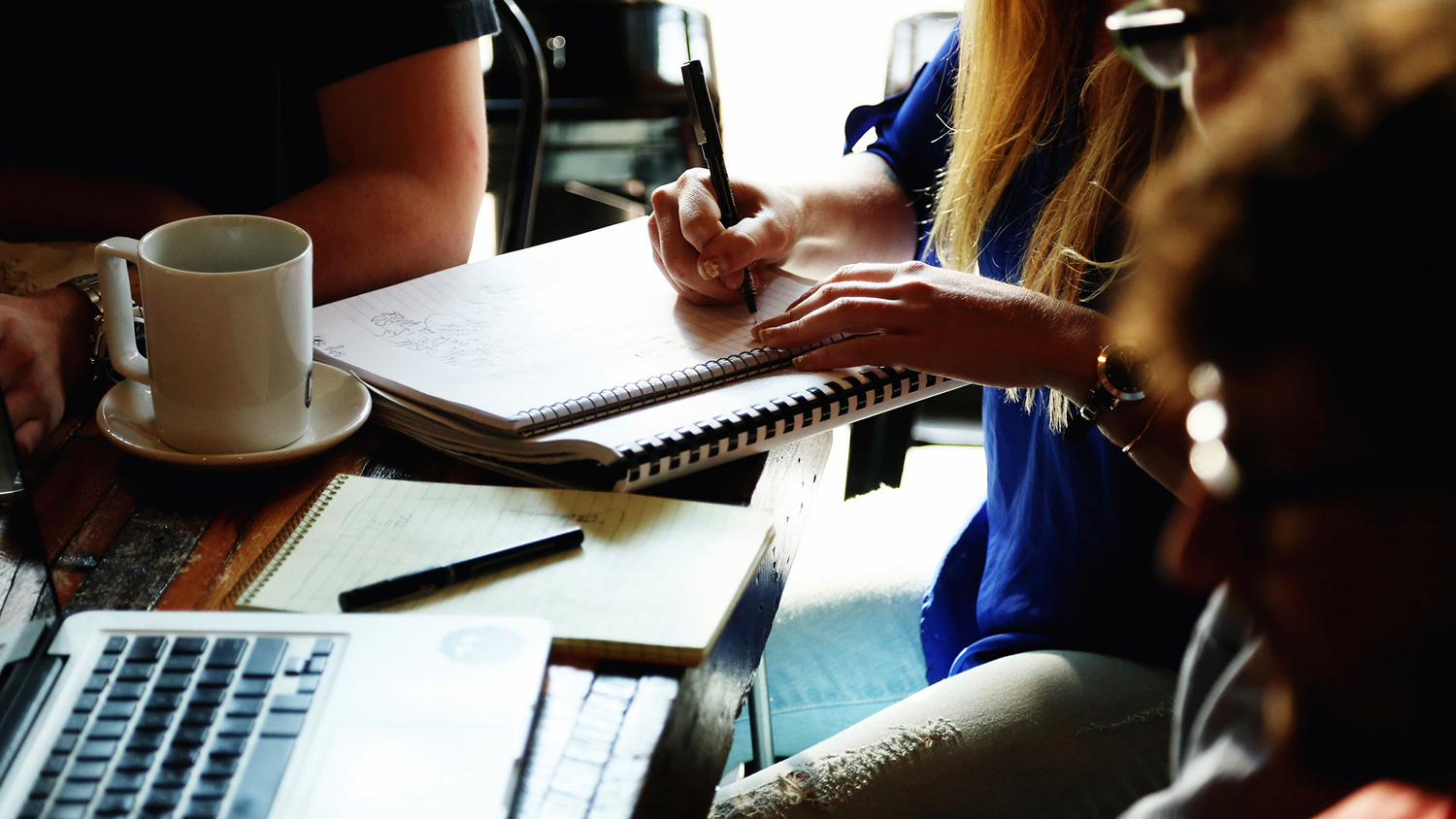 hands, notebooks and computers on the table of people who are working