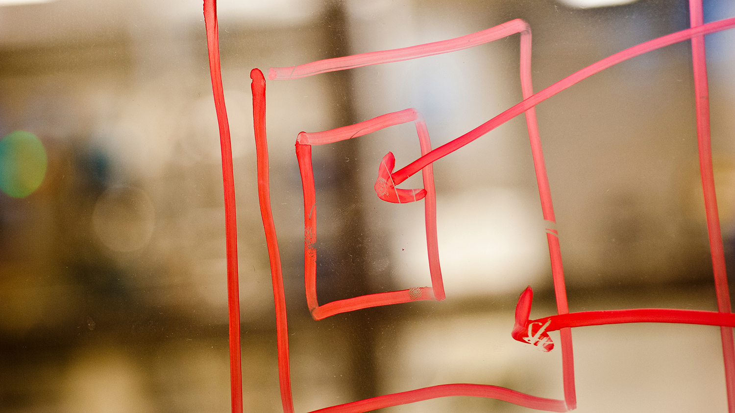 用红色记号笔在一块背光玻璃上画的正方形和箭头。