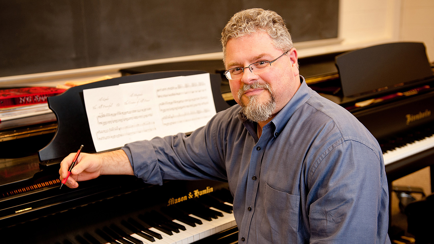 J. Mark Scearce，艺术教授和设计，坐在钢琴上。