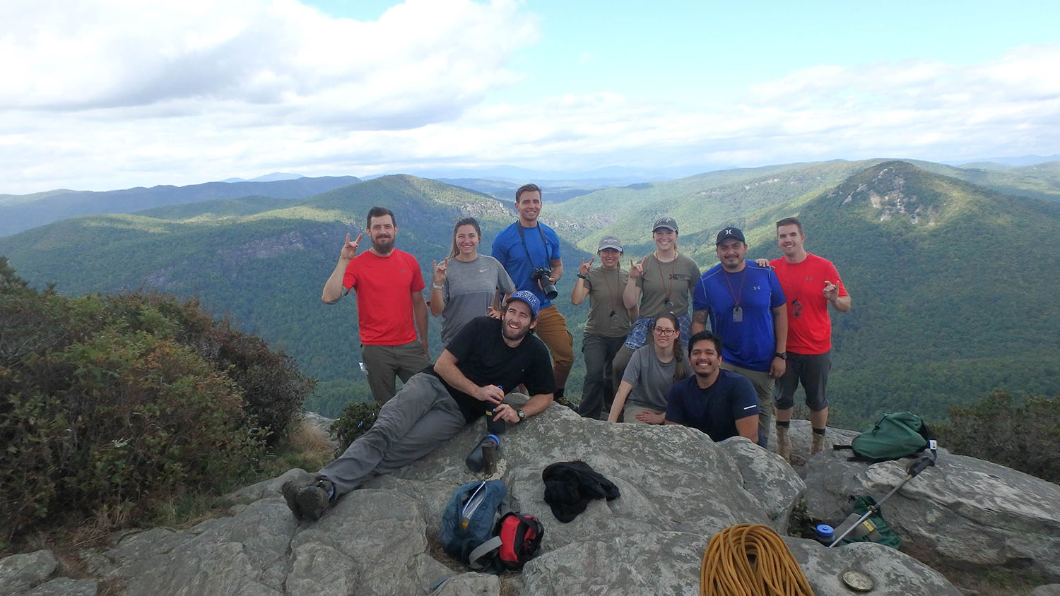 10个微笑的人们为一个小组照片姿势在山顶部
