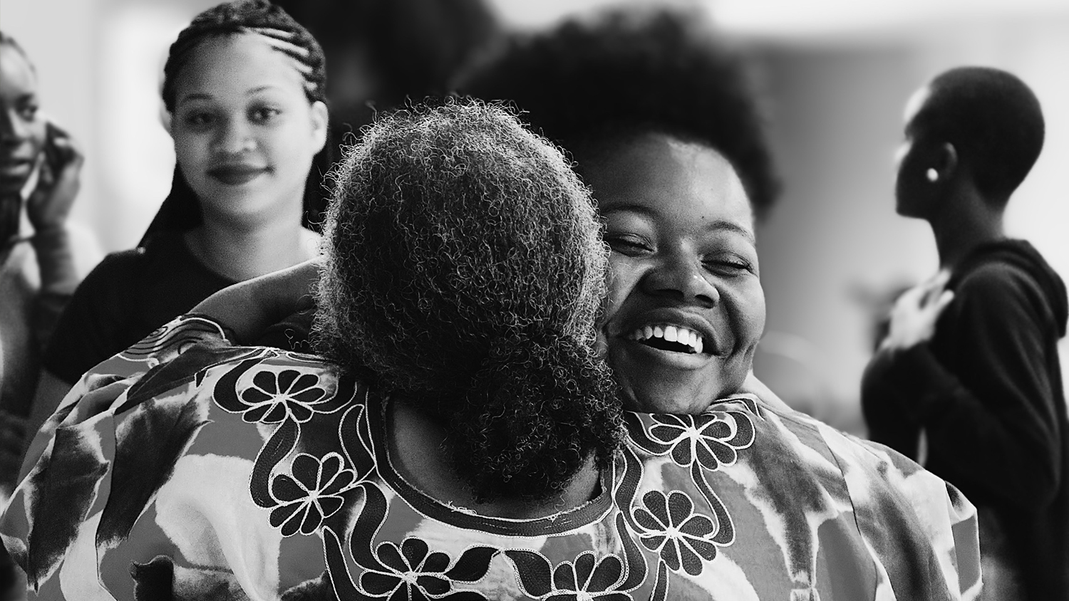 在这张黑白照片中，两位非裔美国妇女拥抱在一起。