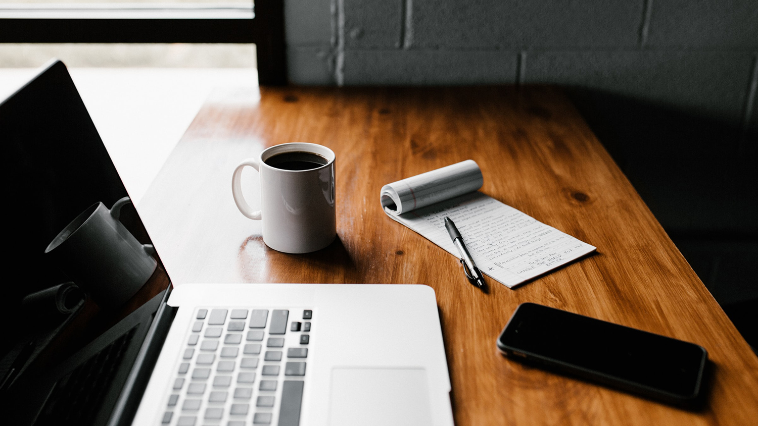 Table with laptop, smartphone and coffee cup.