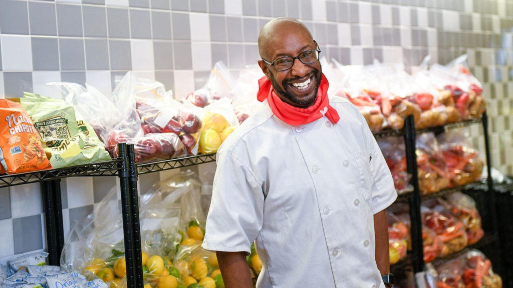 站立在生产的架子前面的人在食物储藏室