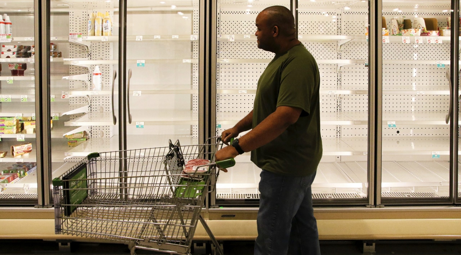 超市购物者推着购物车经过空冰箱箱