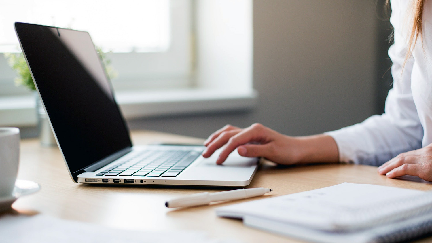 女人的手在桌上的笔记本电脑上打字