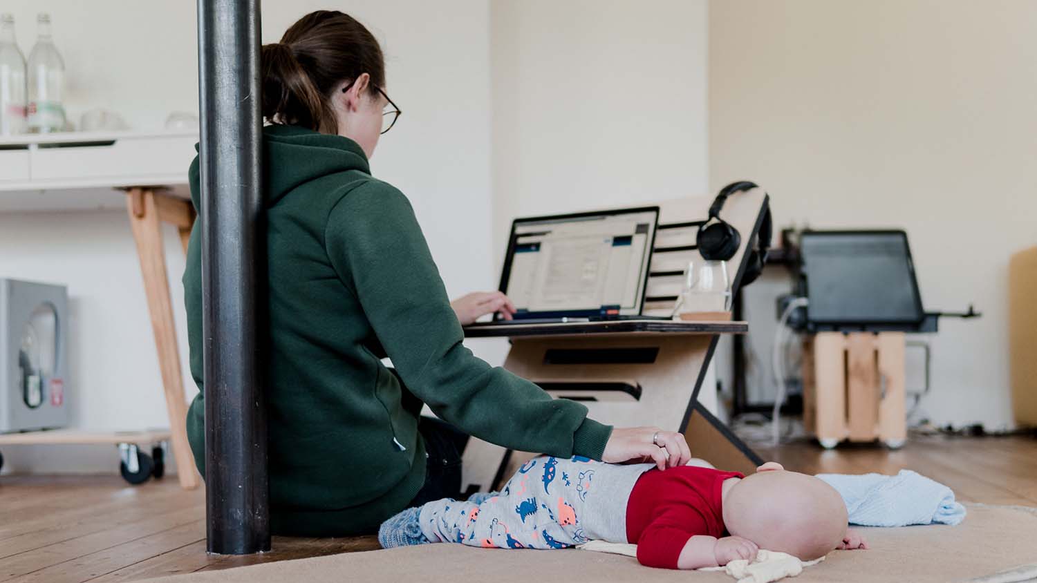 妈妈一边用一只手拍拍宝宝，一边用另一只手操作笔记本电脑