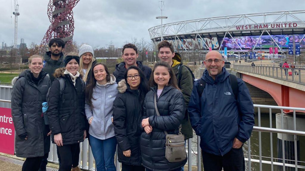 教授和学生在伦敦体育场面前姿势。