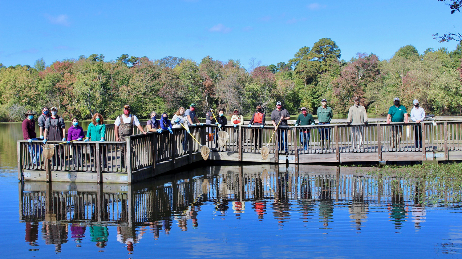 在罗利湖，学生在收集有关鱼群数据的一天后站在码头上。
