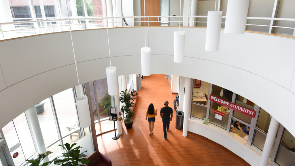 两个人穿过NC国家学生卫生服务大楼内的开放空间。