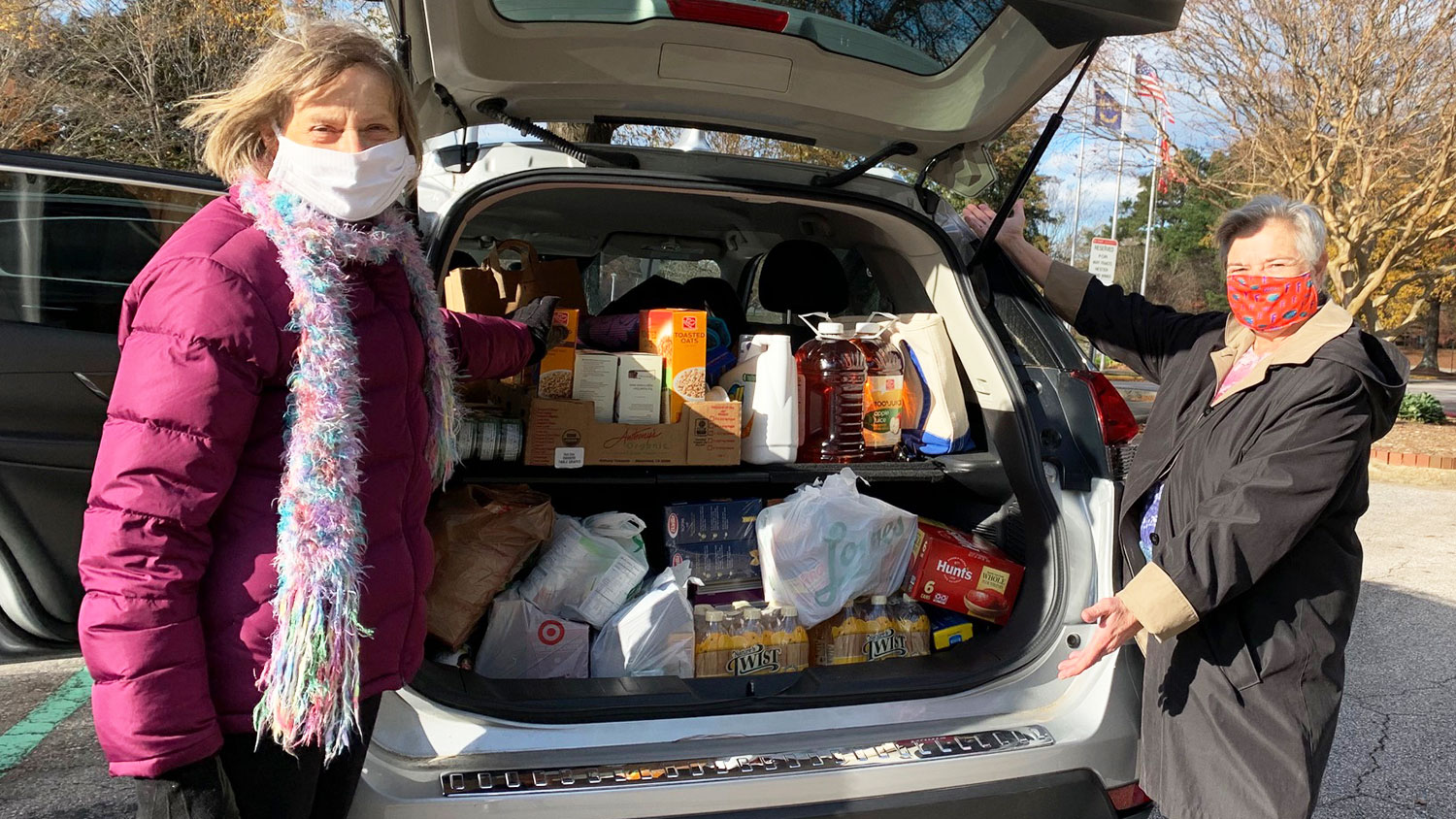 两个女人站在装满捐赠食物的车旁
