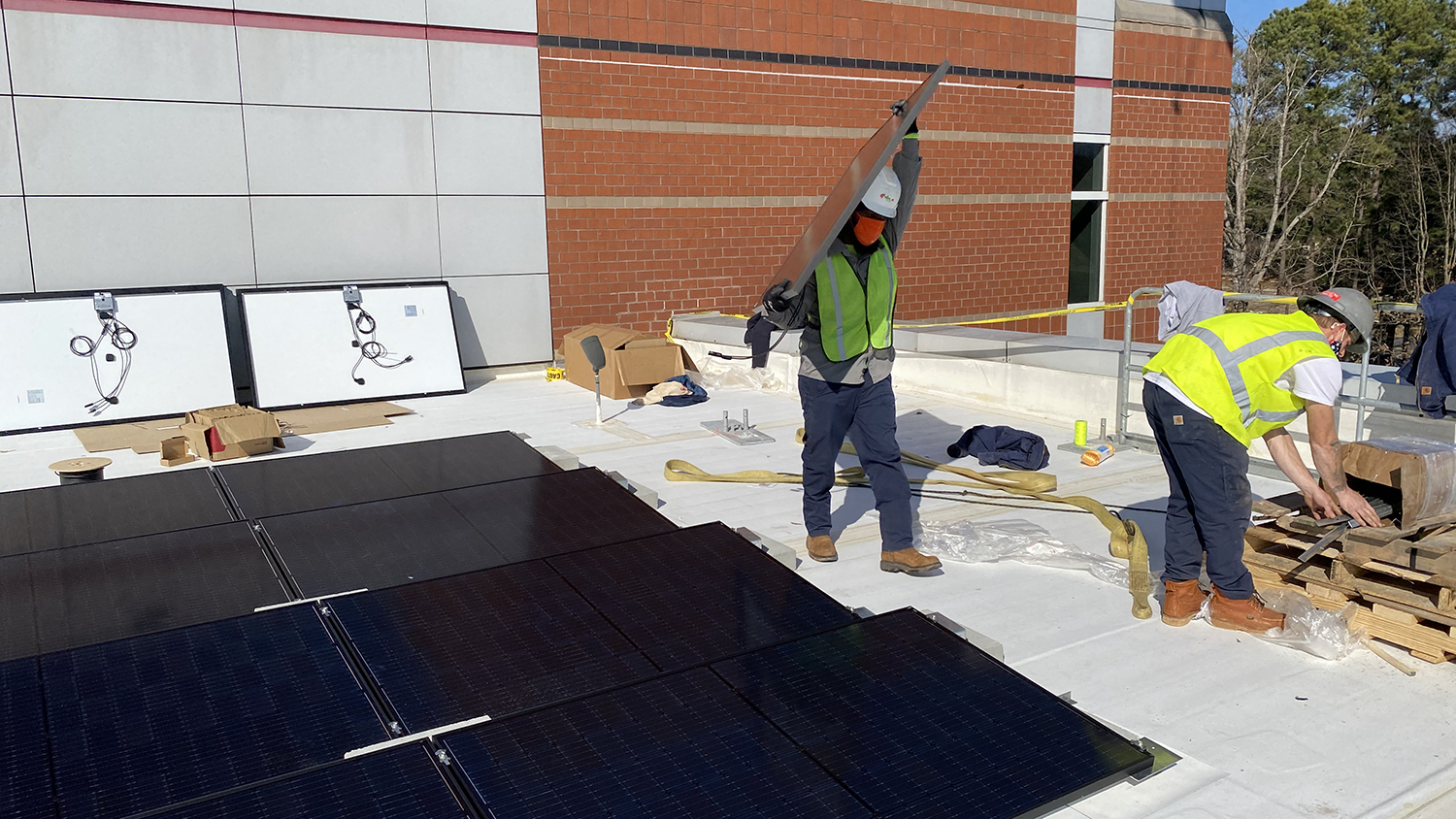 工人在墨菲中心的屋顶上搬运太阳能电池板。