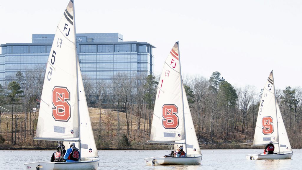 湖面上三艘帆上印有北卡罗来纳州block S标志的帆船