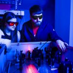 两个年轻的成年人与激光一起工作。