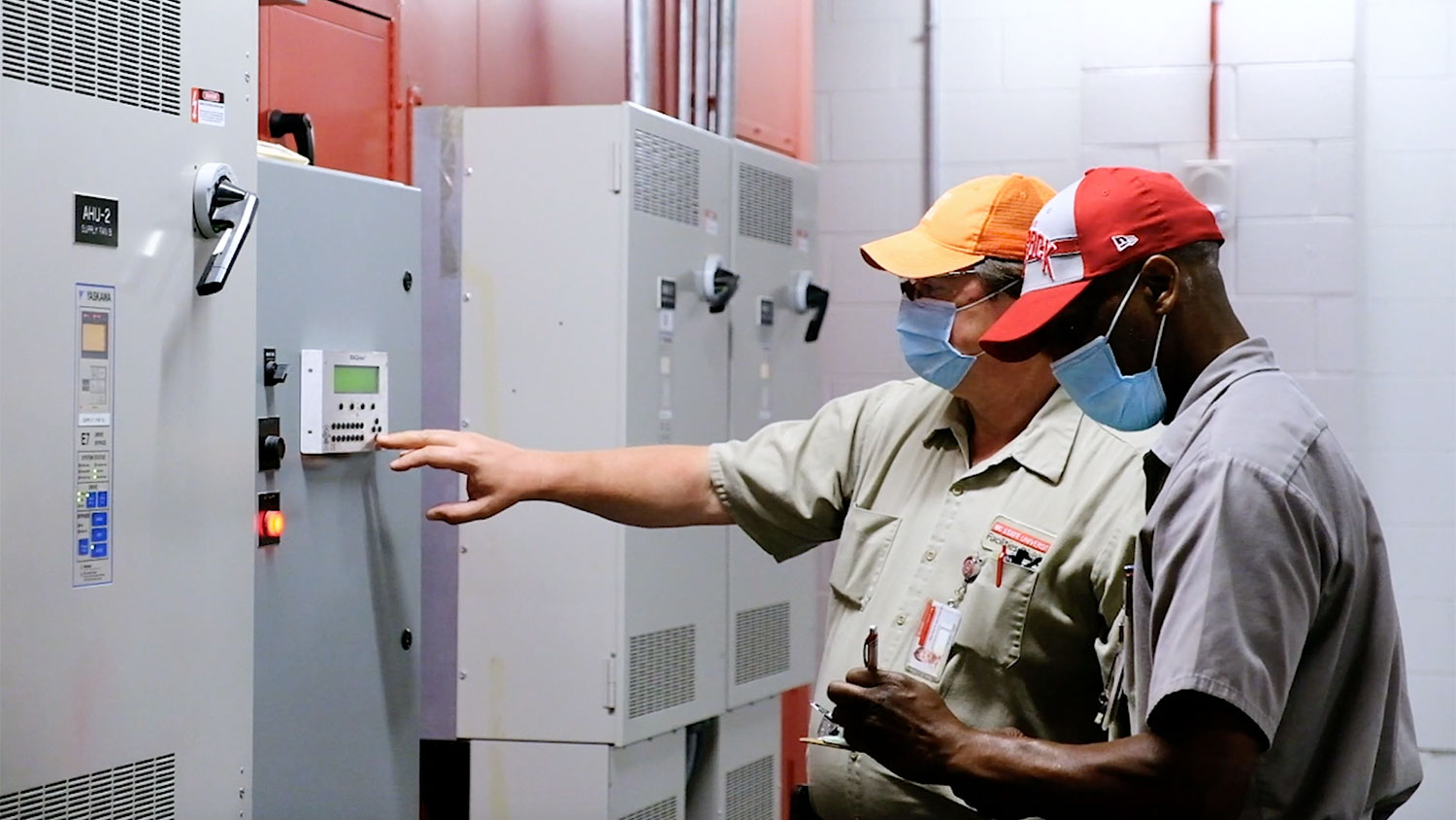 两家工厂的员工司检查校园HVAC系统的控制面板