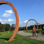 两个人在北卡罗来纳艺术博物馆周围的公园里骑自行车。