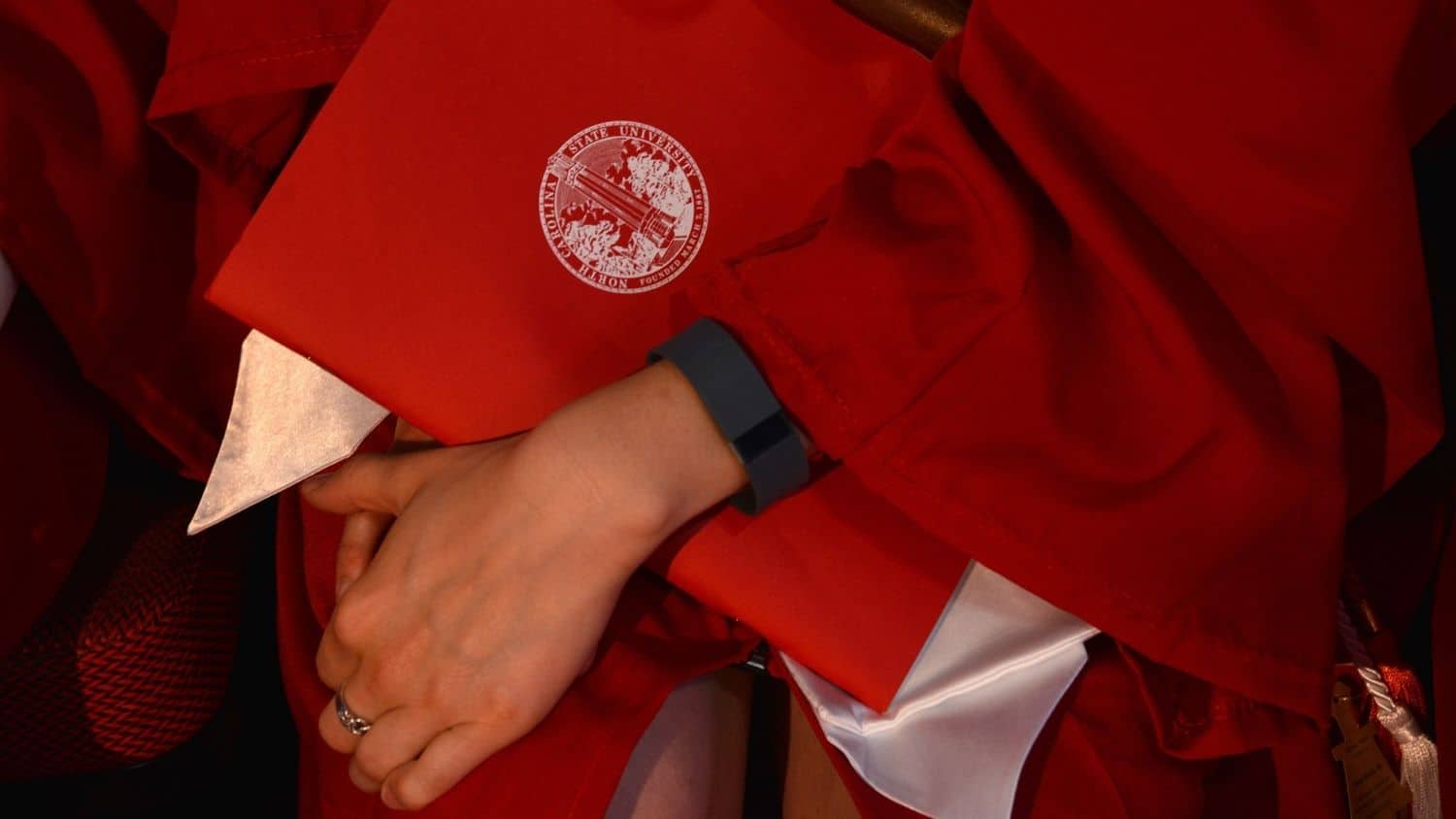 一名北卡州立大学的学生展示他们的帽子和长袍。