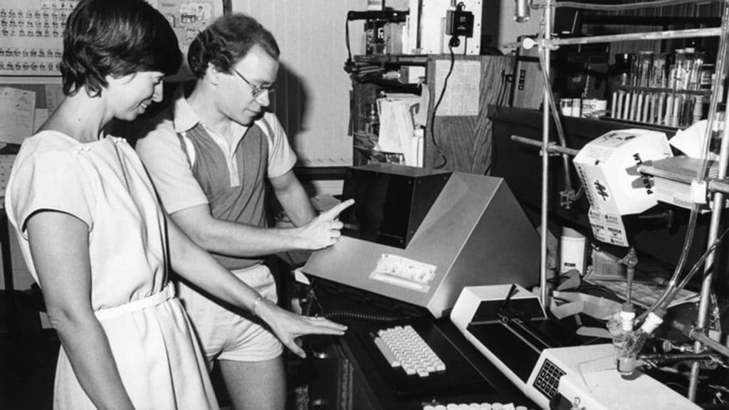 20世纪80年代的照片，Marye Anne Fox检查了未识别的同事的实验室设备。
