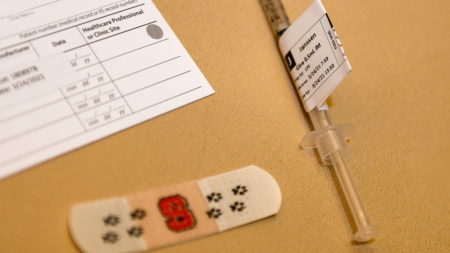 一张疫苗卡，一块北卡罗莱纳州标签的绷带和一个装有詹森疫苗的注射器