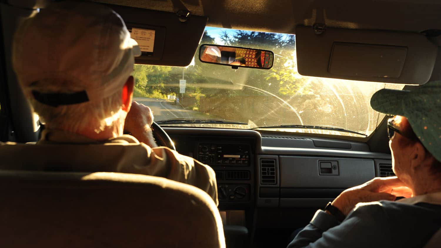 年长的男人和女人坐在汽车的前座。