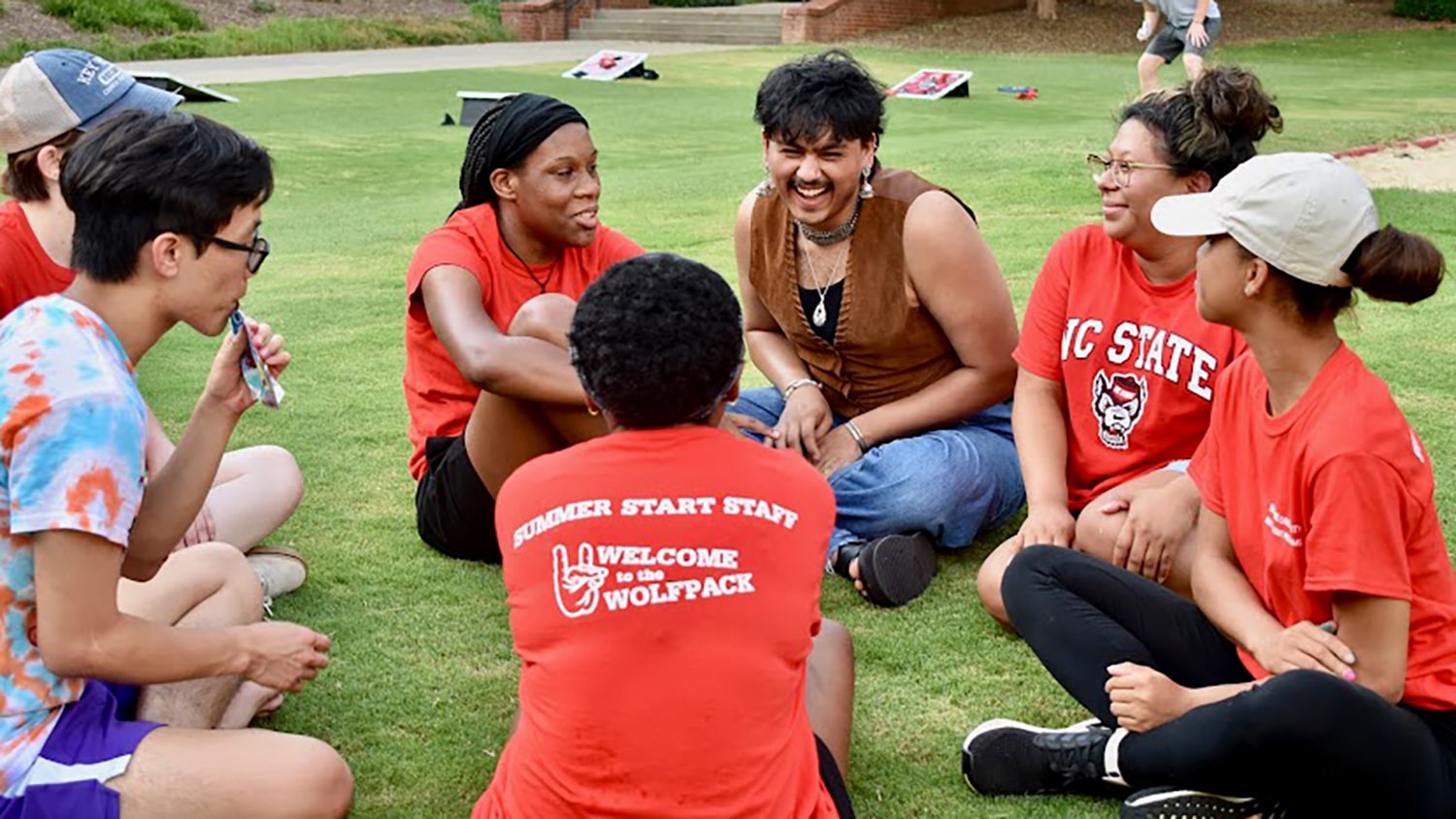 参加夏季开始的学生坐在塔克大厅外的草坪上，并在夏季开始活动期间进行社交活动。