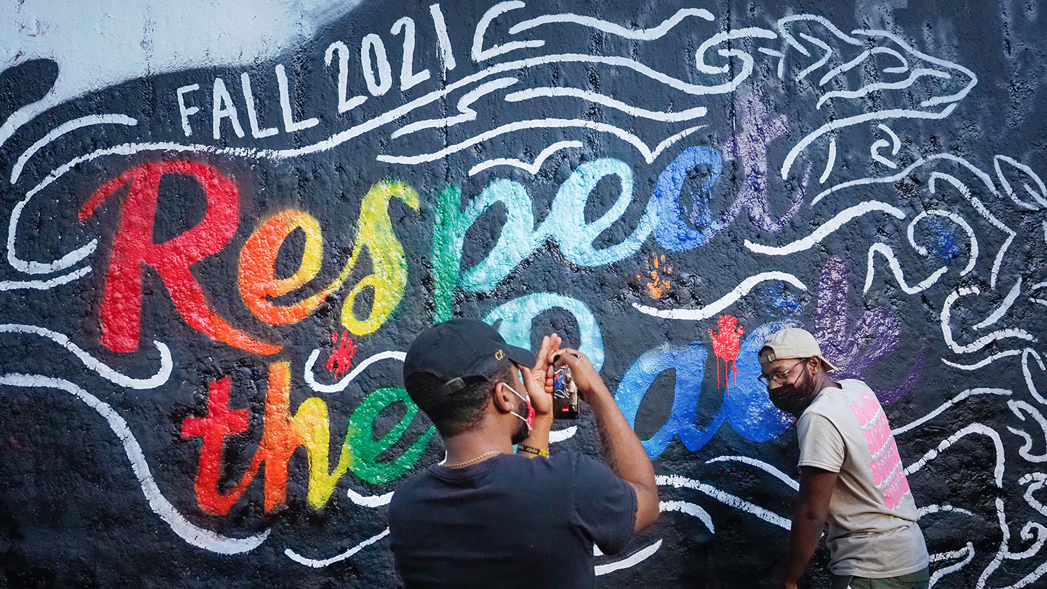 一名学生拍摄另一名学生的照片留下他们的手印包壁画。