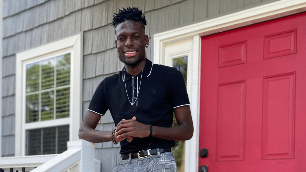 阿瑞斯·埃普斯站在一座有红门的建筑物外。