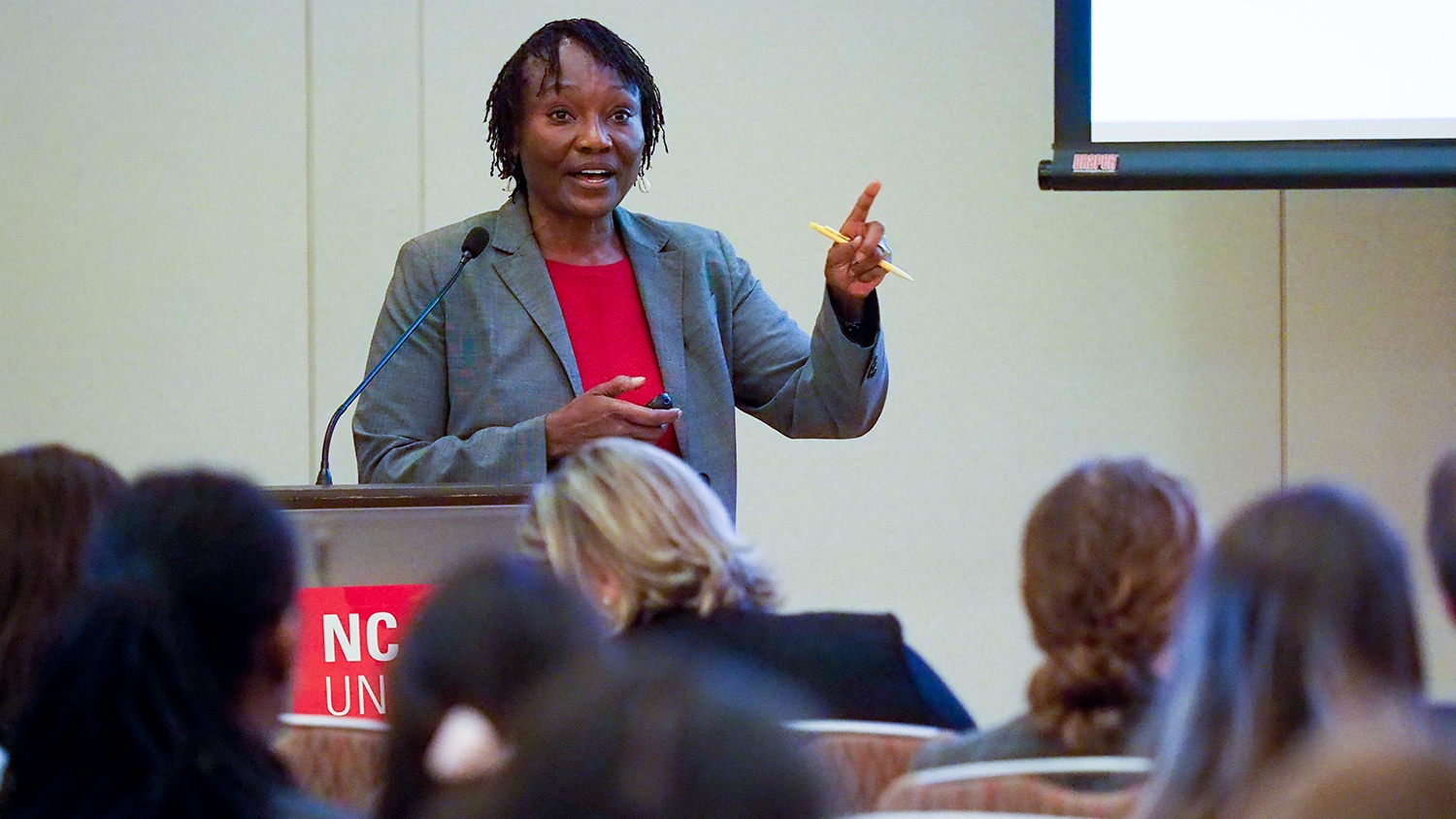 Cathrine Hoyo stands behind a lectern while presenting research at the CHHE Symposium.