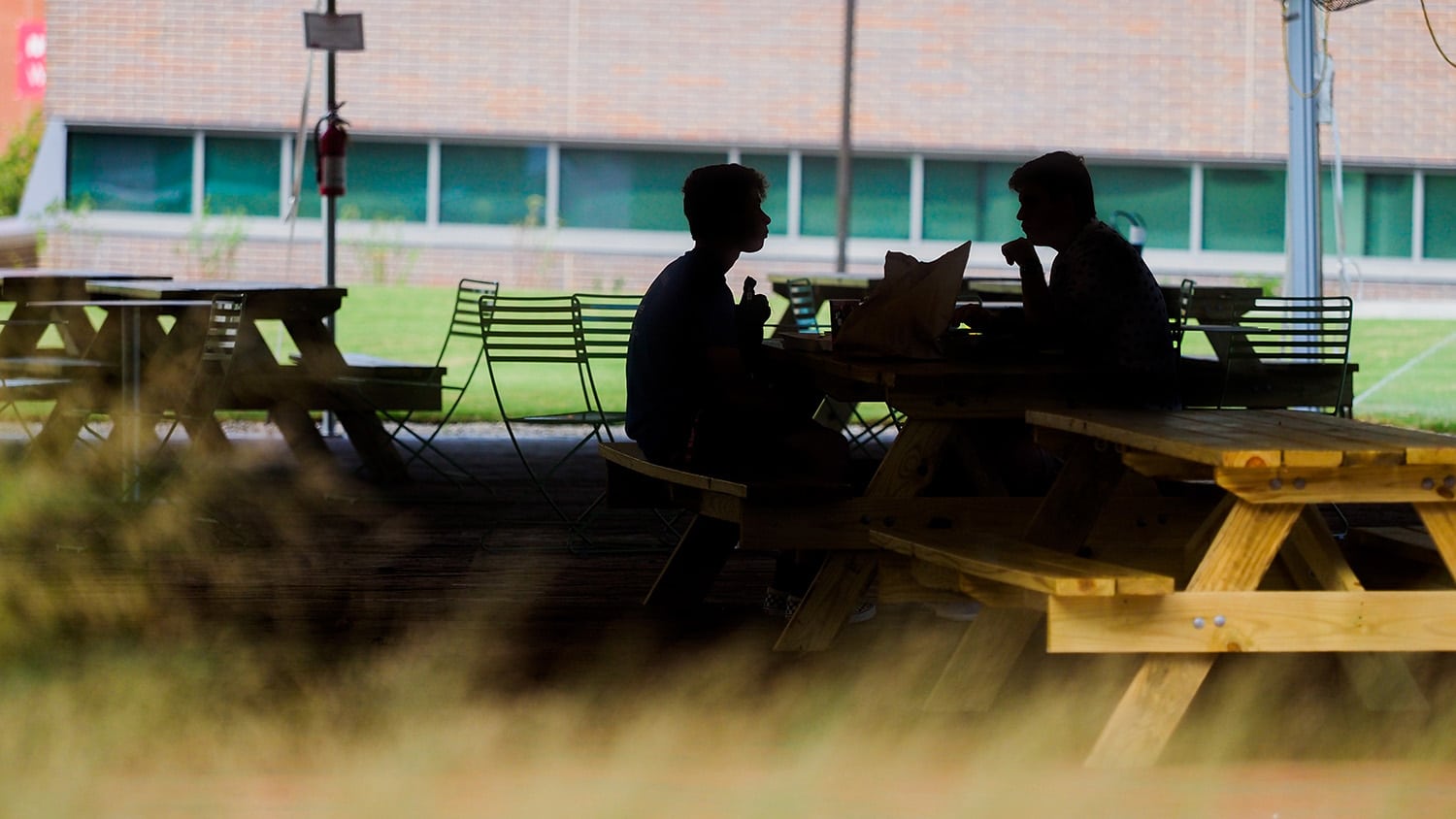 两个人，在阴影中，在北卡州立大学的野餐桌上聊天