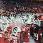 北卡罗来纳州篮球队站在场边，身后是座无虚席的体育场。