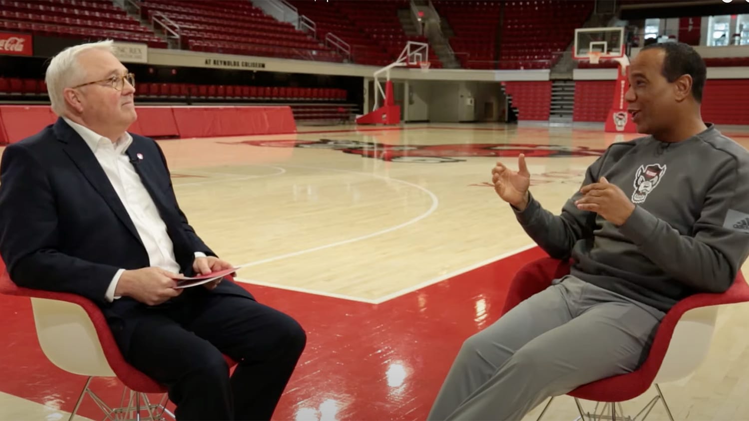 兰迪·伍德森和凯文·济慈坐在篮球场上交谈。
