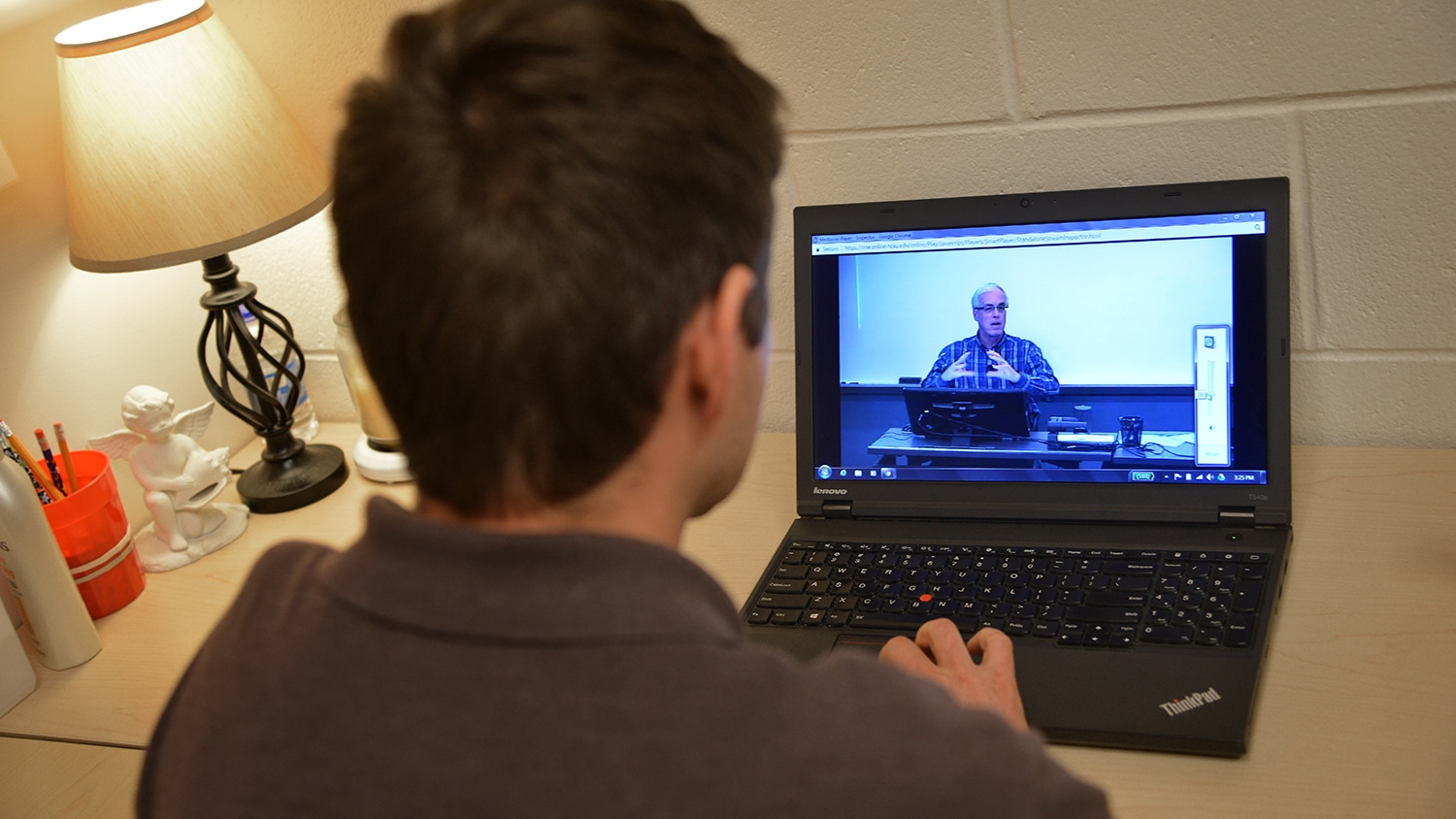 越过学生在电脑旁的肩膀的镜头。