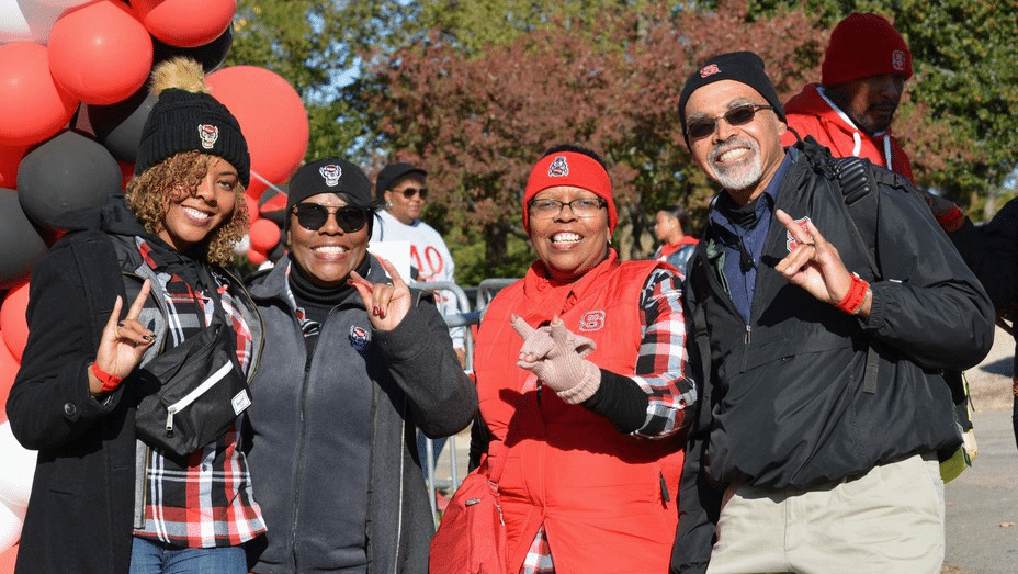 A group of alumni throw up wolf hands during a Black Alumni Society event.