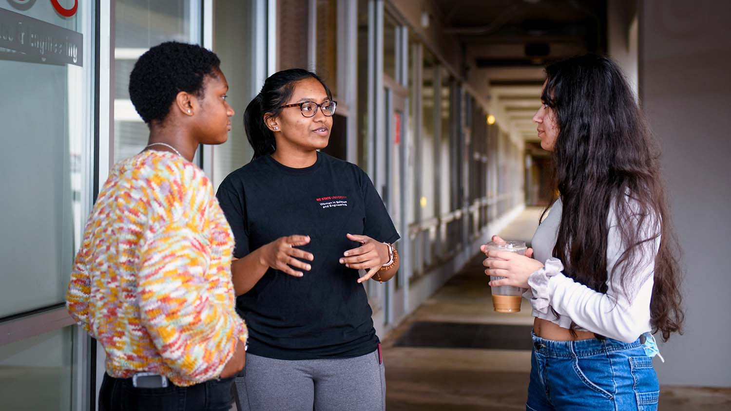 Three students talking outside the WISE office.