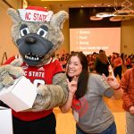 Students pose with Mr. Wuf at a student giving event.