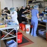 Students standing around operating tables in lab.