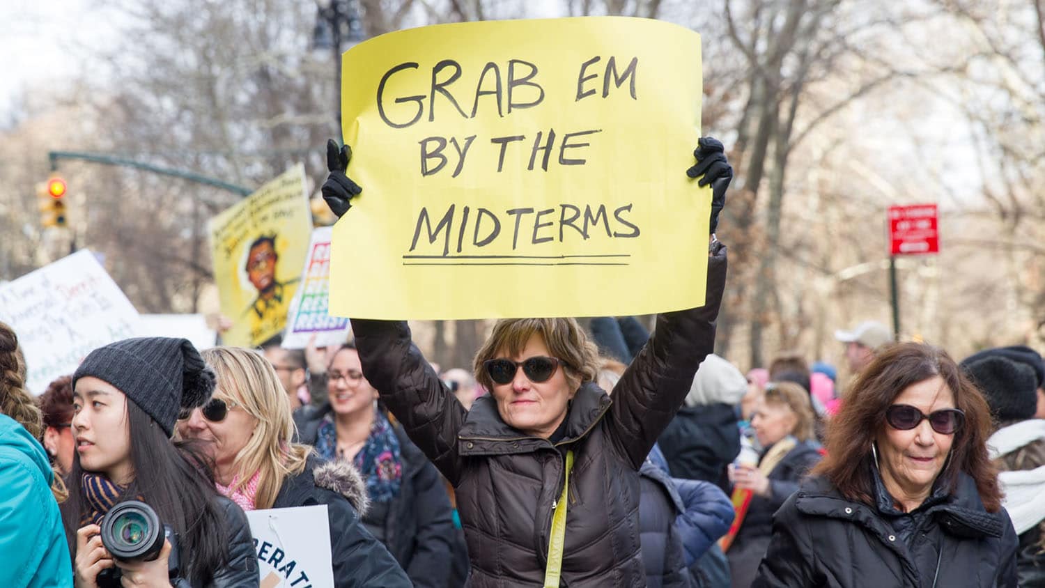 woman at a political demonstration holds a sign reading 