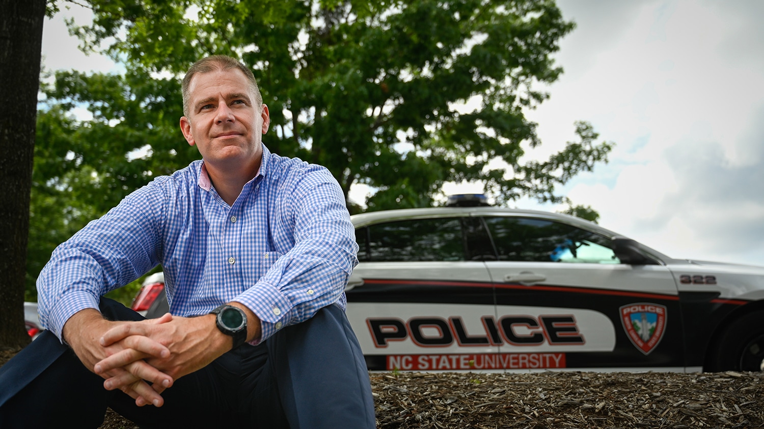 Ian Kendrick sitting on steps with a police car in the background.