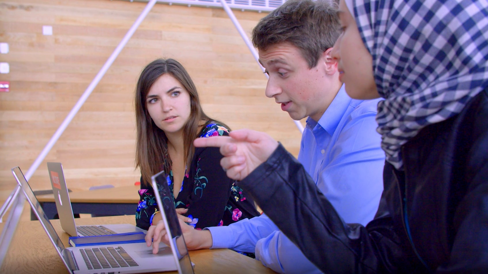 三个人一边用笔记本电脑一边聊天。